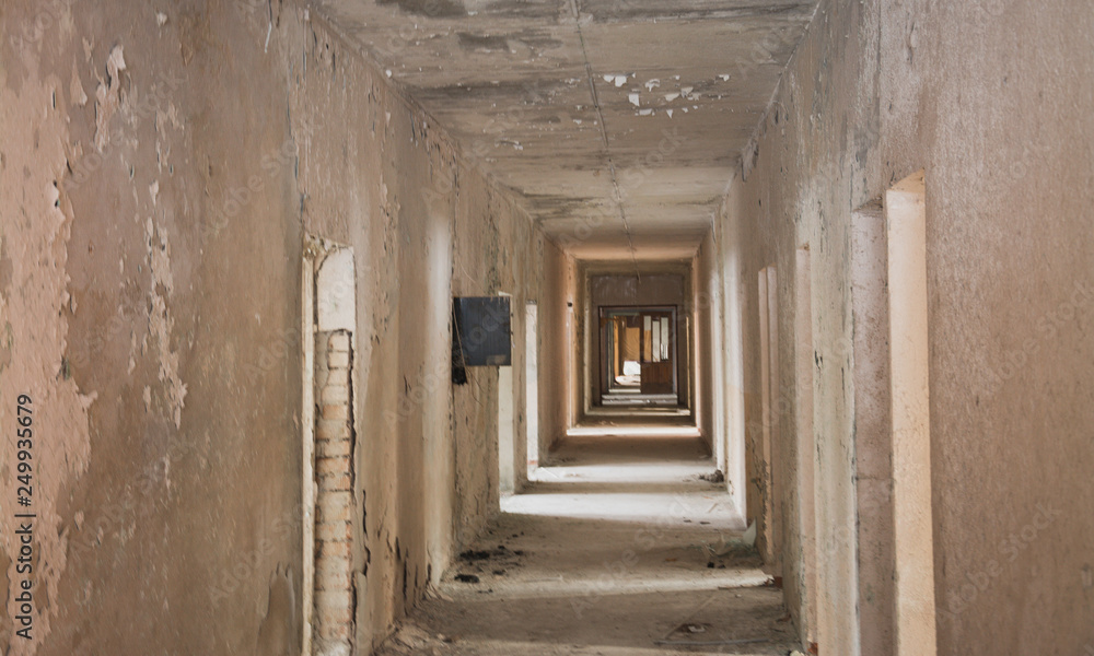 The interior of an abandoned old building. A long corridor with entrances to rooms without doors.