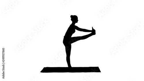 Silhouette Beautiful young fit woman in sportswear doing sport exercise, bending in variation of Utthita Hasta Padangusthasana, Dandayamana-Janushirasana. photo