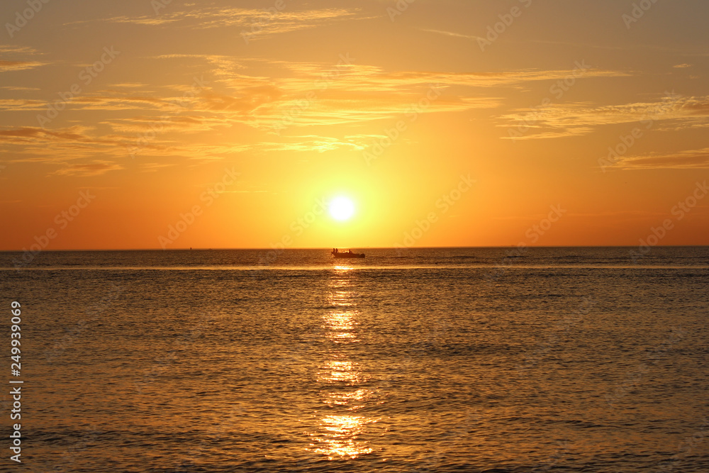 Boat in Orange Sunset, Boat with people sitting on bow centered under sunset, Gorgeous Florida Sunset