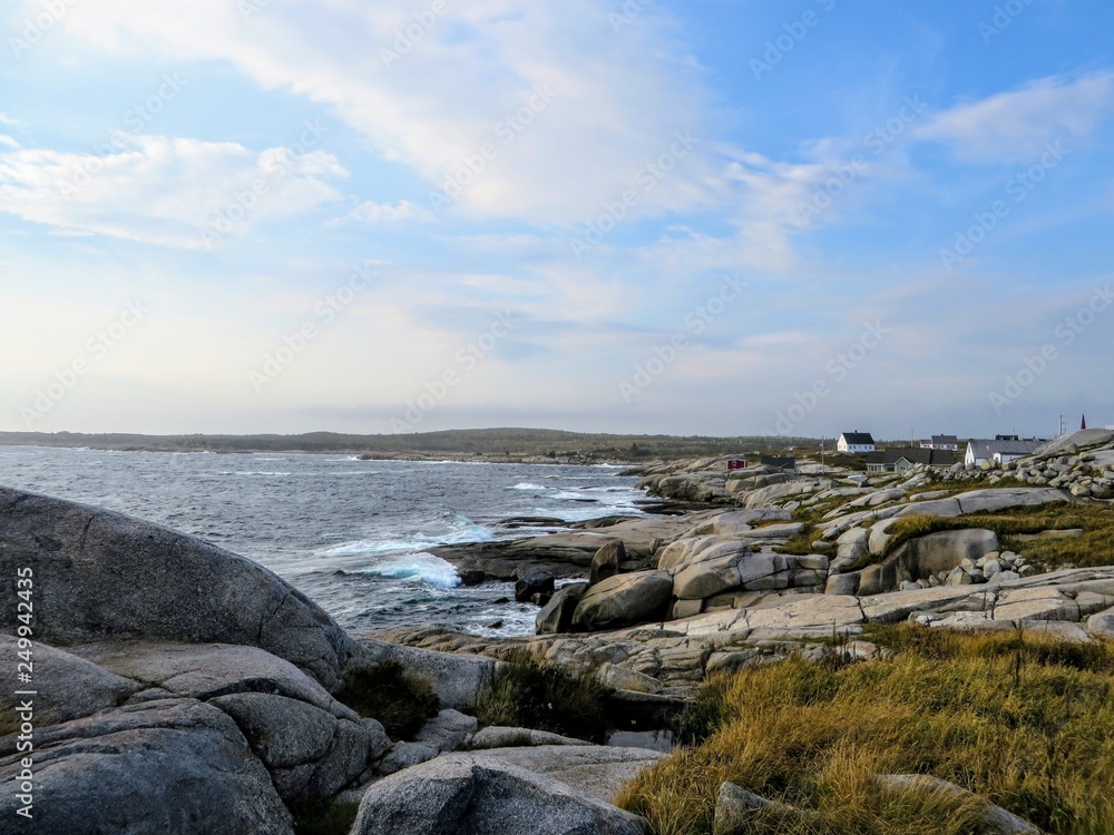 The rugged coast off of Peggys Peggys Cove Lighthouse, an active lighthouse and an iconic Canadian image, in Nova Scotia, Canada.  Waves from the atlantic ocean crash against the rocky shore.