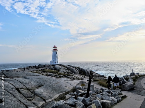 Visitors walking towards Peggys Point Lighthouse, also known as Peggys Cove Lighthouse, an active lighthouse and an iconic Canadian image.