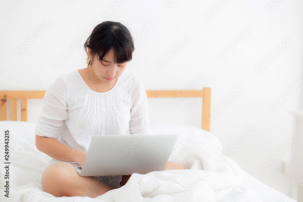 Portrait of beautiful asian young woman sitting on bed using laptop computer at bedroom for leisure and relax, freelance with girl working notebook, communication and lifestyle concept. Portrait of beautiful asian young woman sitting on bed using laptop computer at bedroom for leisure and relax, freelance with girl working notebook, communication and lifestyle concept.