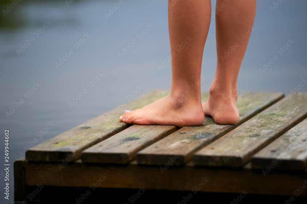 Feet of a young girl on a small pier.