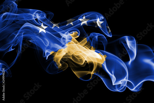 National flag of Kosovo made from colored smoke isolated on black background. Abstract silky wave background.