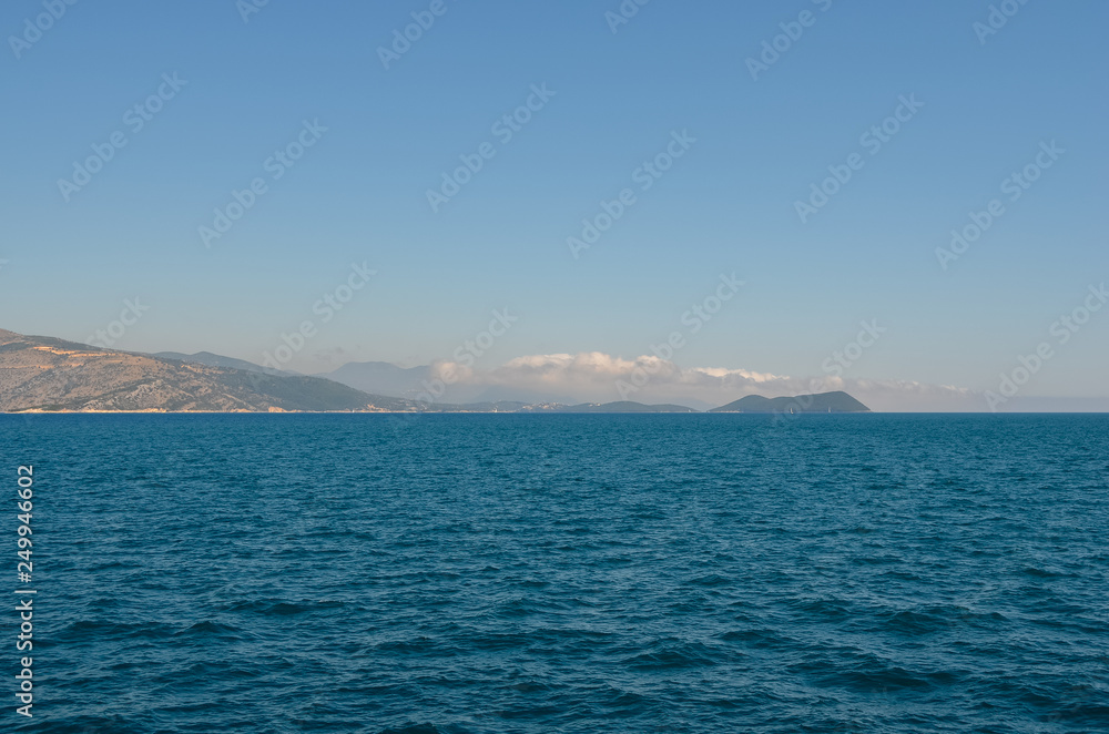 View of greek island against clear blue sky from ferry . Greece coastline . Summer vacation View of greek island against clear blue sky from ferry . Greece coastline . Summer vacation