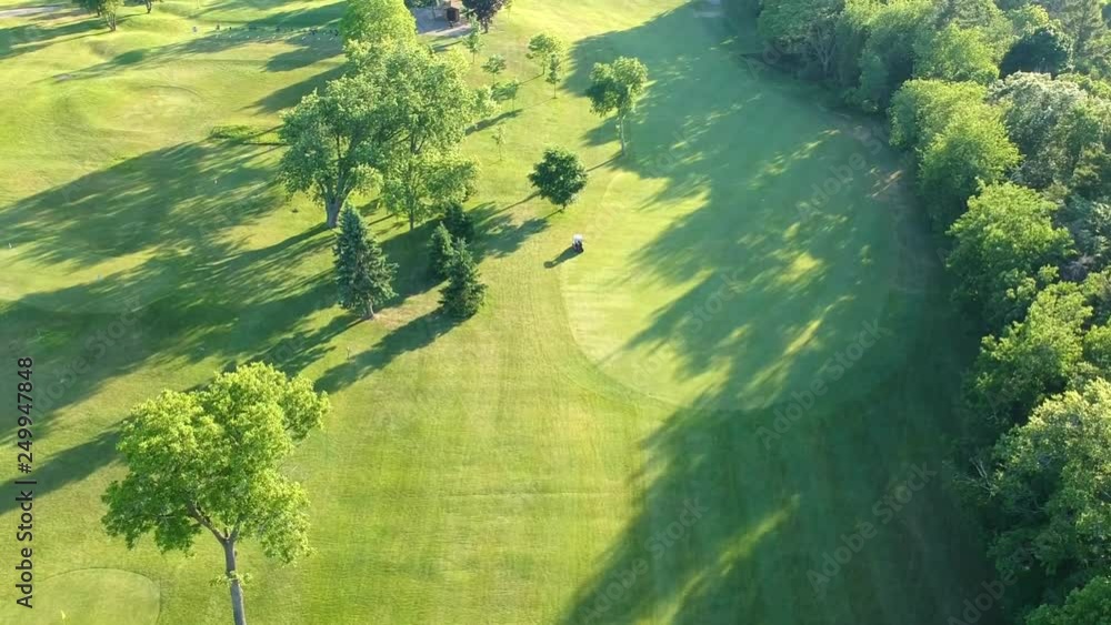 Aerial landscape flight over green golf course and golf scooter. Aerial landscape flight over green golf course and golf scooter.