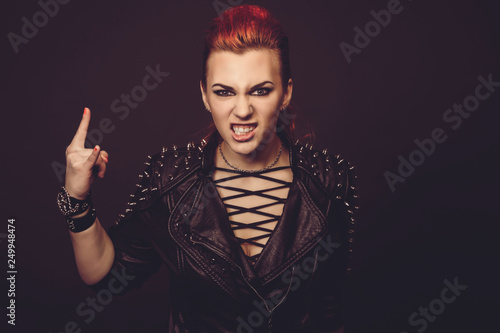 Fototapeta Portrait of a young punk woman with dark leather jacket isolated in studio on black background