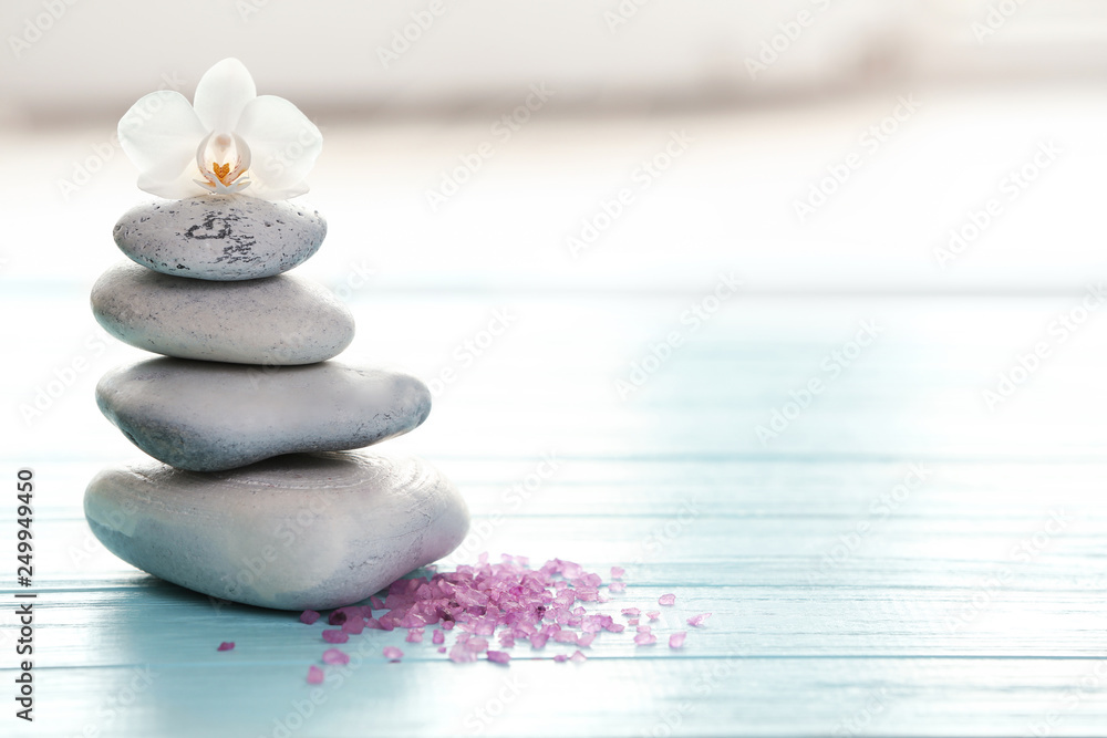 Spa stones, sea salt and flower on table against blurred background. Space for text - obrazy, fototapety, plakaty 