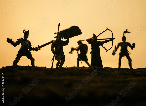 Medieval battle scene with cavalry and infantry. Silhouettes of figures as separate objects, fight between warriors on sunset foggy background. © zef art
