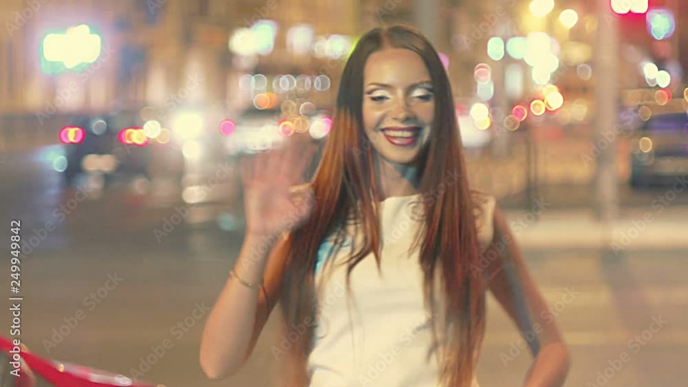 Beautiful young woman in night city saying hello to camera Beautiful young woman in night city saying hello to camera