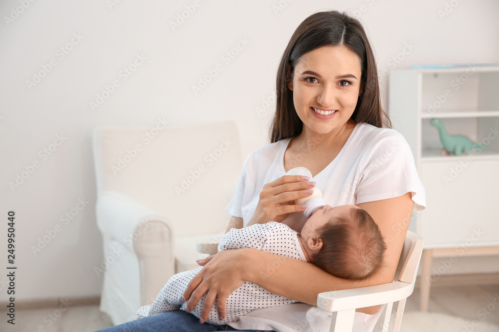 Woman feeding her baby from bottle in nursery at home. Space for text Woman feeding her baby from bottle in nursery at home. Space for text