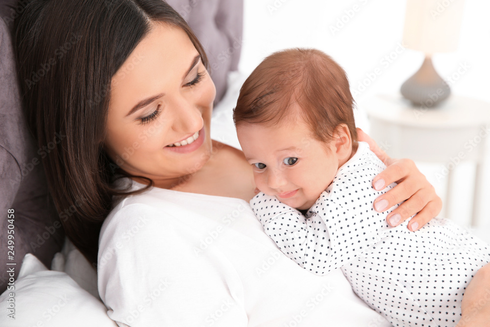 Happy woman with her cute baby on bed
