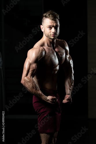 Muscular Man Flexing Muscles In Gym