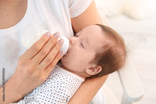 Woman feeding her baby from bottle at home, closeup