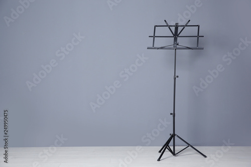 Empty music note stand near grey wall indoors. Space for text photo