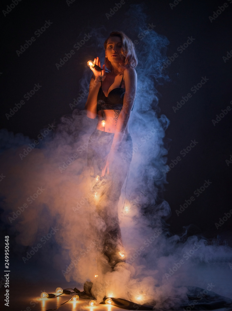 A beautiful girl with smoke, and keeps the bulbs warm. A warm and cold light. Artistic Photography