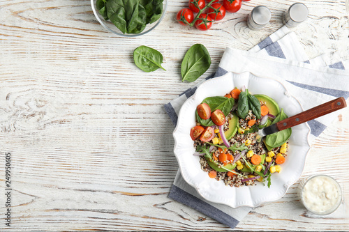 Healthy quinoa salad with vegetables in plate served on table, top view. Space for text