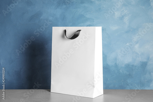 Paper shopping bag on table against color background. Mock up for design
