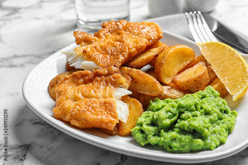 Plate with British traditional fish and potato chips on marble table, closeup