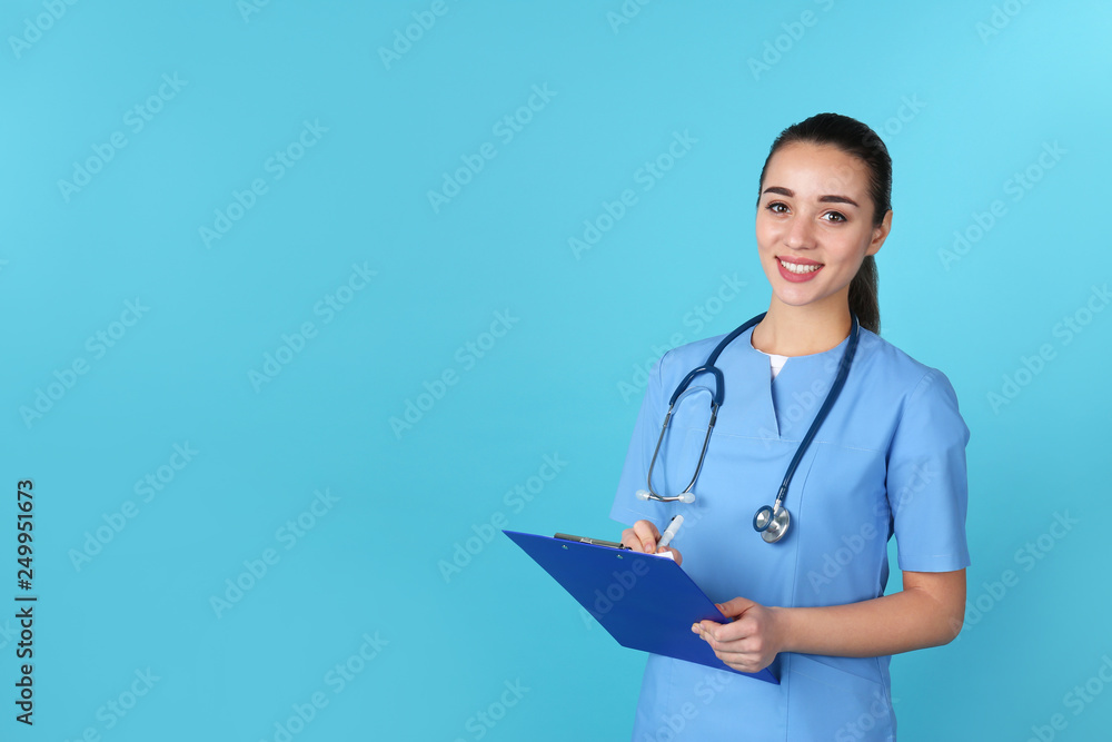 Young medical student with clipboard on color background. Space for text Young medical student with clipboard on color background. Space for text