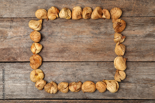 Frame made of figs on wooden background, top view with space for text. Dried fruit as healthy food