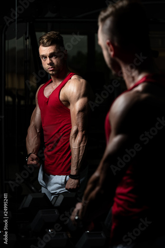 Handsome Young Man Standing Strong In The Gym And Flexing Muscles - Muscular Athletic Bodybuilder Fitness Model Posing After Exercises © Jale Ibrak