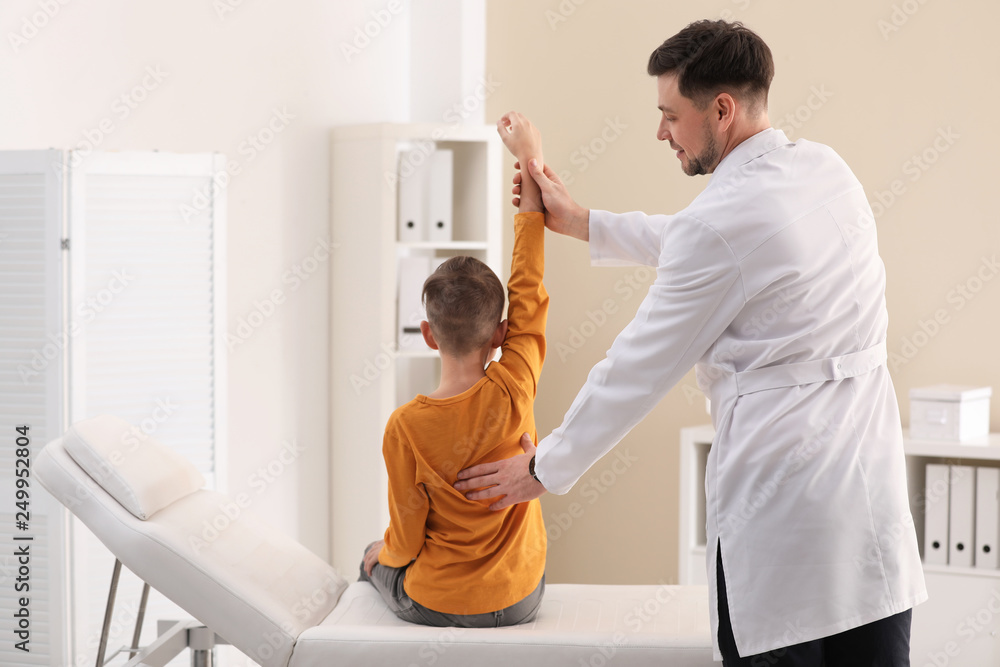 Fototapeta premium Chiropractor examining child with back pain in clinic