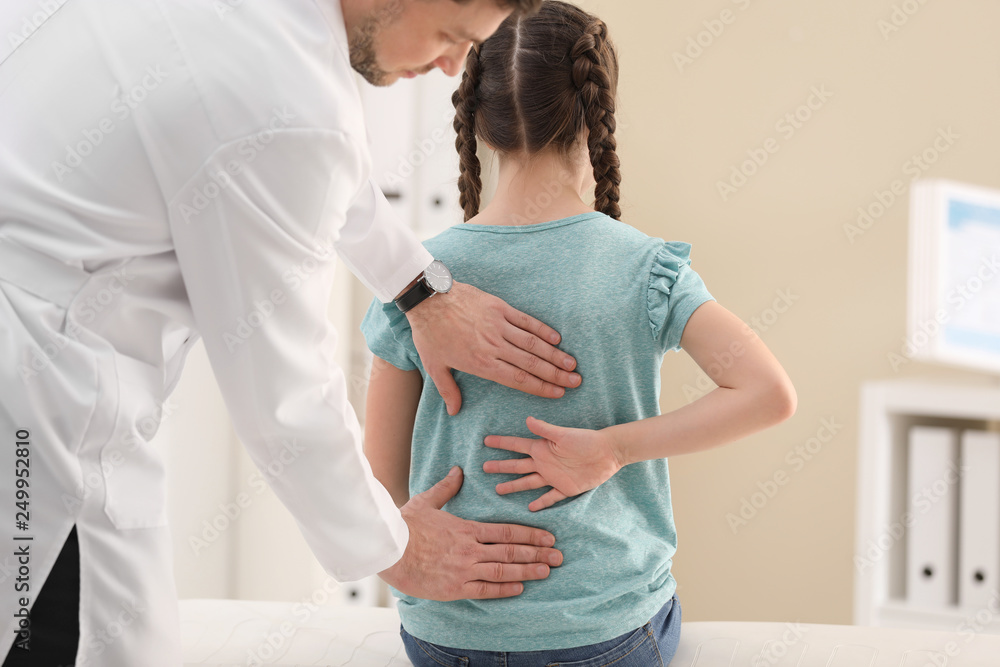 Fototapeta premium Chiropractor examining child with back pain in clinic
