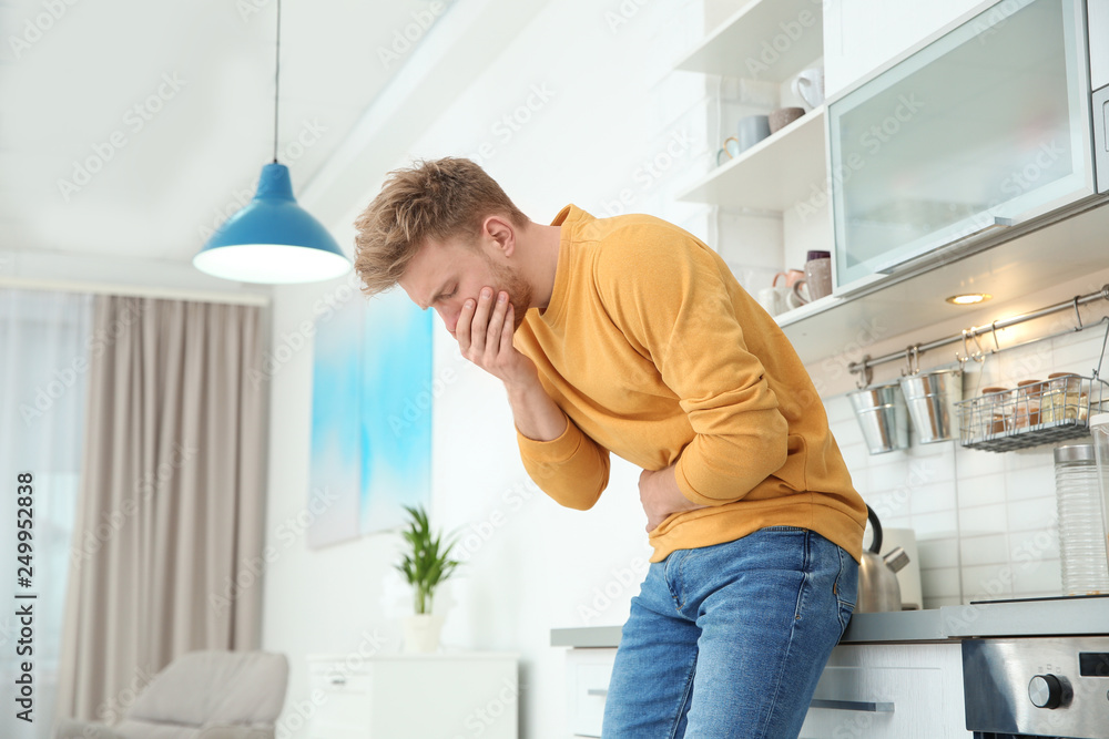 Young man having nausea in kitchen. Space for text Young man having nausea in kitchen. Space for text