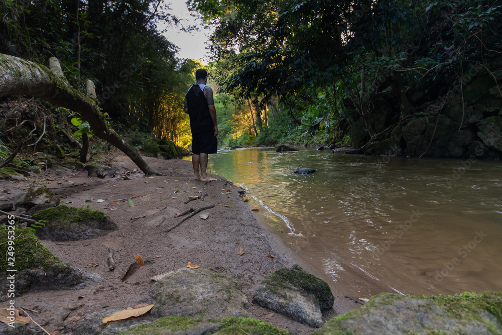 Man relaxing and meditating beside a river in nature Man relaxing and meditating beside a river in nature
