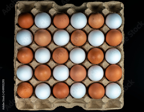 packing of yellow and white chicken eggs arranged in a diagonal composition on a black background