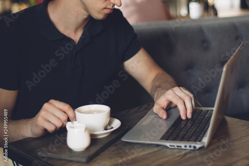Businessman working on a laptop and using phone in a cafe.