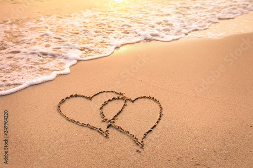 Romantic honeymoon holiday or Valentine's day on the beach concept with two hearts drawn on the sand, tropical getaway for couples, love symbol photo