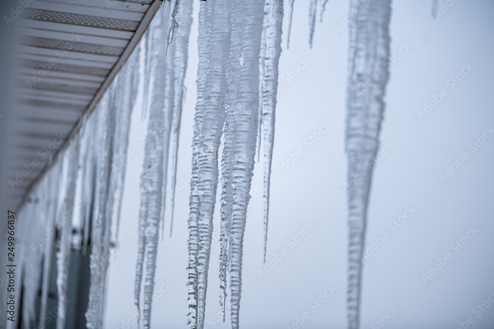 Icicles against the gray sky on the roof of the town house Icicles against the gray sky on the roof of the town house