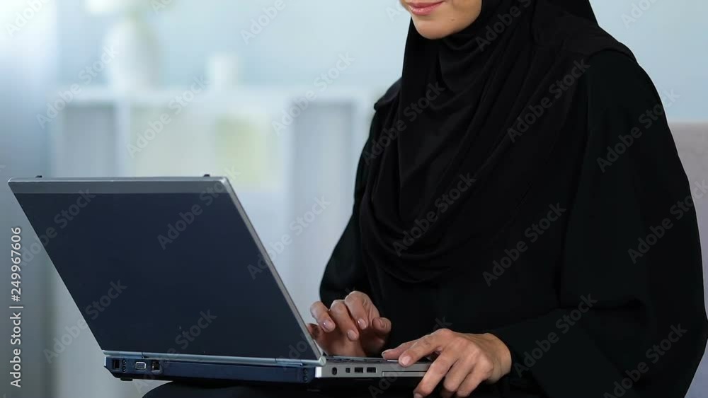 Muslim woman typing on laptop computer, working at home, freelance or education Muslim woman typing on laptop computer, working at home, freelance or education