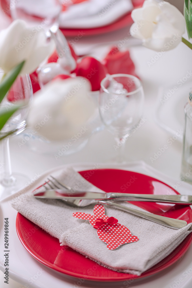 Happy easter. Decor and table setting of the Easter table is a vase with white tulips and dishes of red and white color. Easter colored eggs with white polka dots. Happy easter. Decor and table setting of the Easter table is a vase with white tulips and dishes of red and white color. Easter colored eggs with white polka dots.