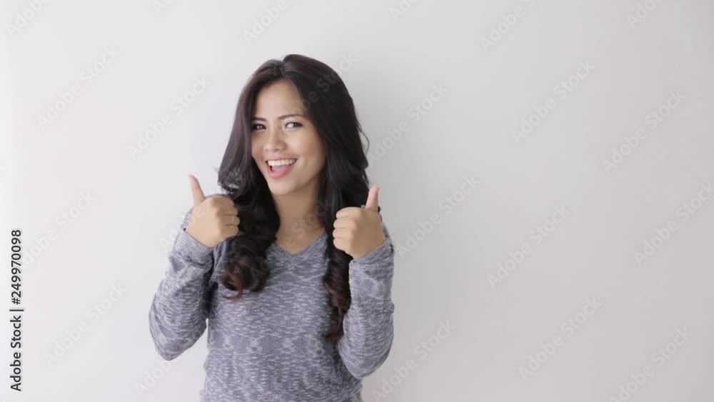 young asian woman showing two thumbs up standing against the wall young asian woman showing two thumbs up standing against the wall