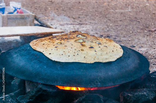 Valokuva Traditional bedouin cake cooking on round semi sphere metal plate on fire in Eil