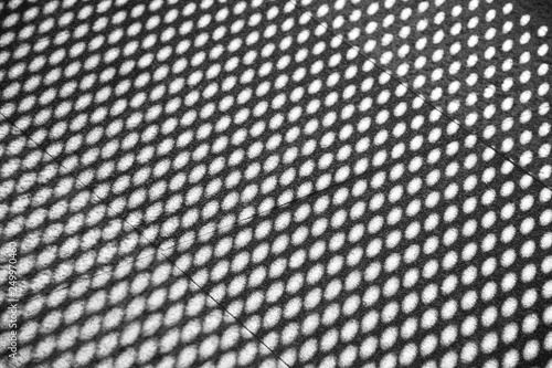 light and shadow of wire mesh on brick floor - monochrome