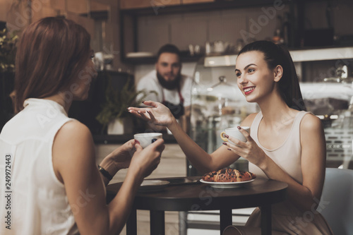 Принти на полотні Two young girls communicate in a cafe at the table