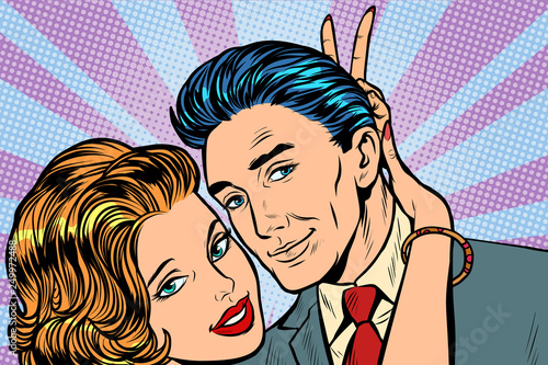 woman puts horns to man, hand gesture joke