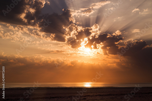 Dramatic sunset with beautful sun beams through the clouds over the Alantic ocean photo