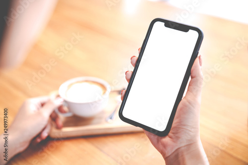 Close up view of Mockup image white screen smartphone on woman's hand. Blank copy space screen for your advertising text message or promotional content. Soft tone