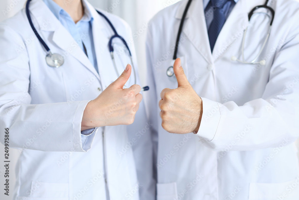 Team of unknown medicine doctors showing OK sign with thumb up close up. Success and high level service in health care, best treatment and customer loyalty and physical concept Team of unknown medicine doctors showing OK sign with thumb up close up. Success and high level service in health care, best treatment and customer loyalty and physical concept