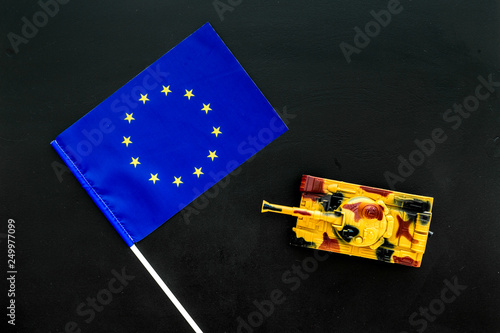 War, military threat, military power concept. European Union. Tanks toy near european flag on black background top view copy space