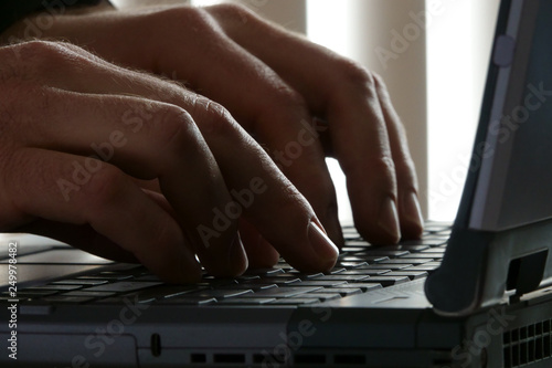 Male Hands Up Close Typing on a Laptop Computer Keyboard in an Office photo
