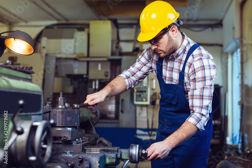 Turner worker is working on a lathe machine in a factory