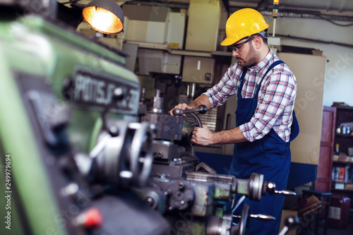 Turner worker is working on a lathe machine in a factory
