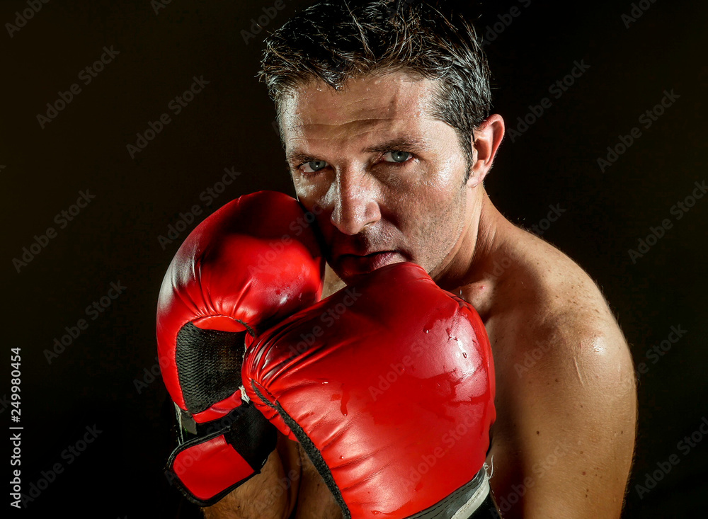young angry and fierce sport man in boxing gloves posing in badass fighter attitude cool and furious in boxer stance isolated on black background in dramatic studio light young angry and fierce sport man in boxing gloves posing in badass fighter attitude cool and furious in boxer stance isolated on black background in dramatic studio light