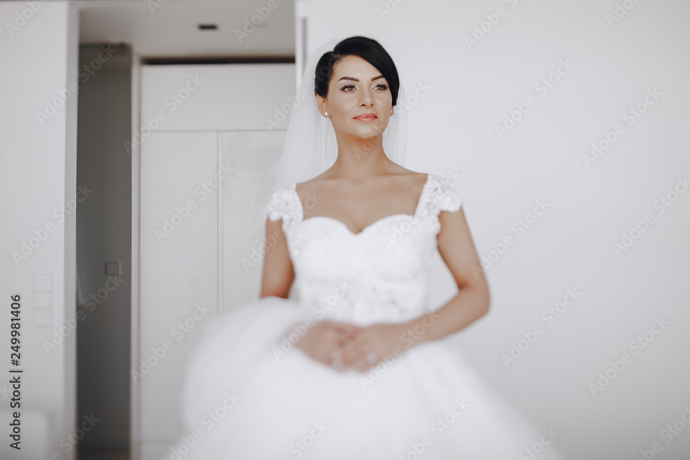 A elegant and beautiful bride at home standing near window A elegant and beautiful bride at home standing near window